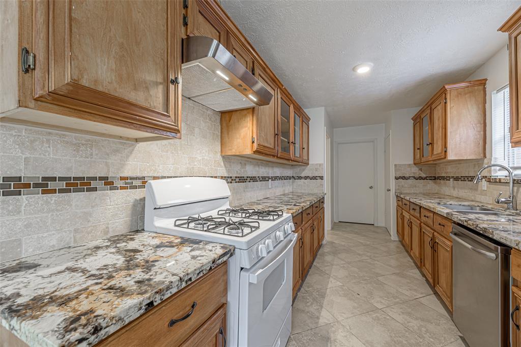 a kitchen with granite countertop a sink stove and cabinets