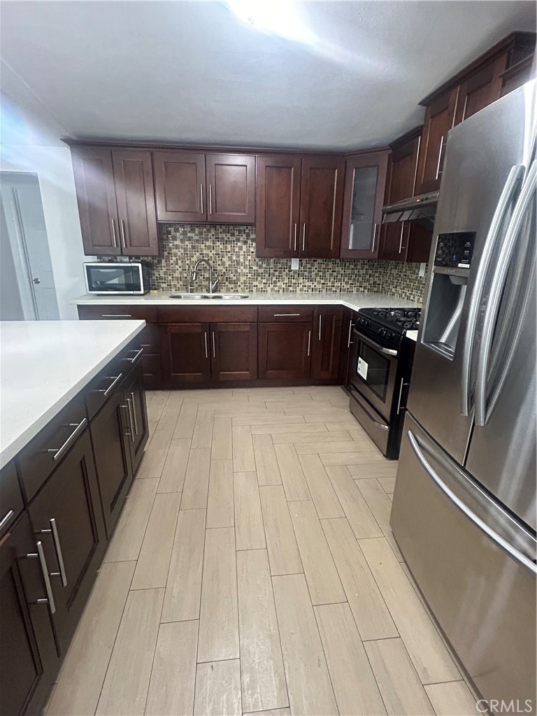 a kitchen with stainless steel appliances granite countertop a sink refrigerator and cabinets