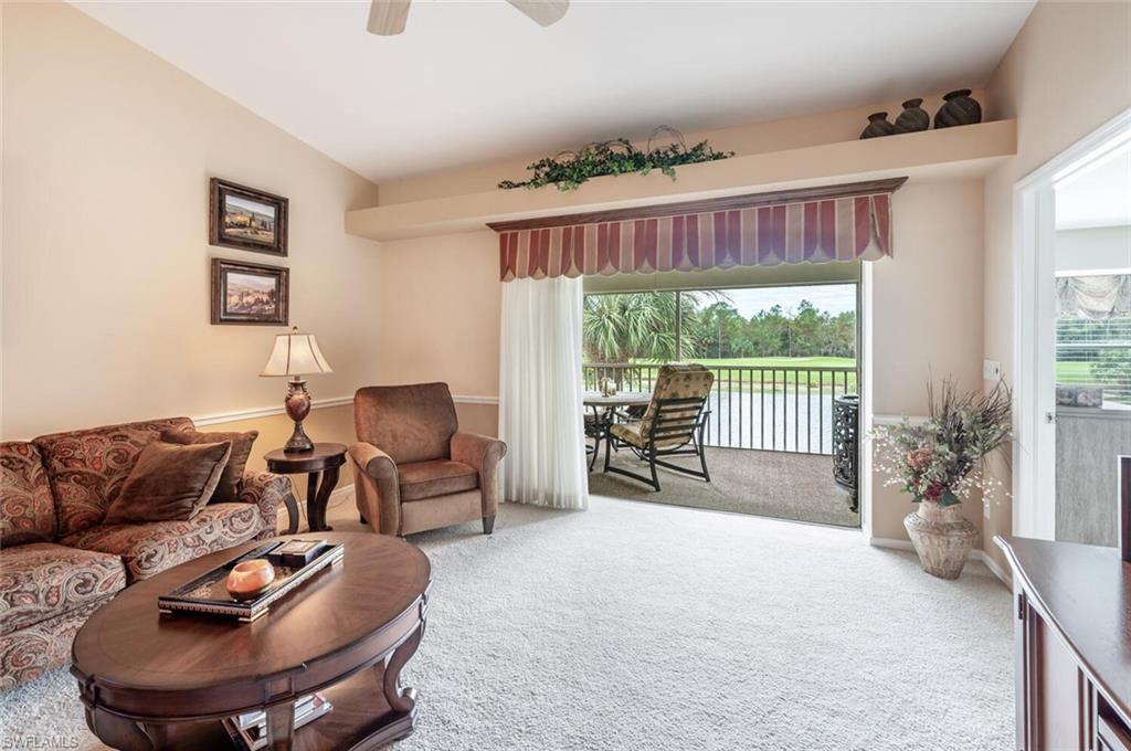 Carpeted living room with vaulted ceiling, ceiling fan, and a healthy amount of sunlight