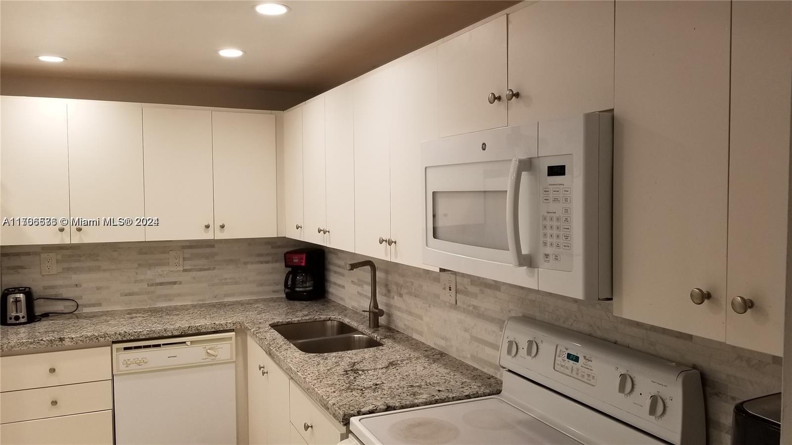 a kitchen with granite countertop white cabinets and white appliances