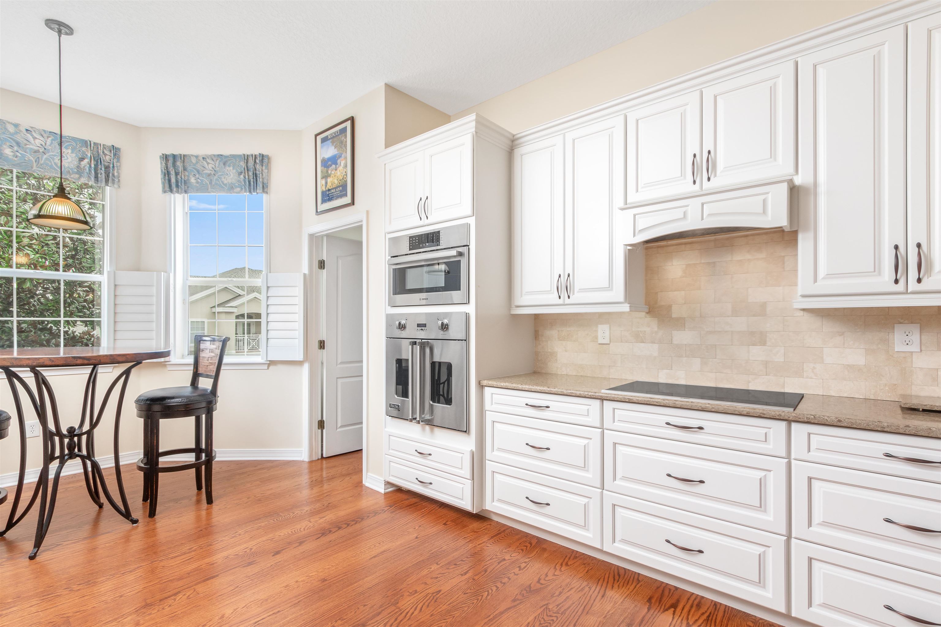 a kitchen with granite countertop a refrigerator and white cabinets