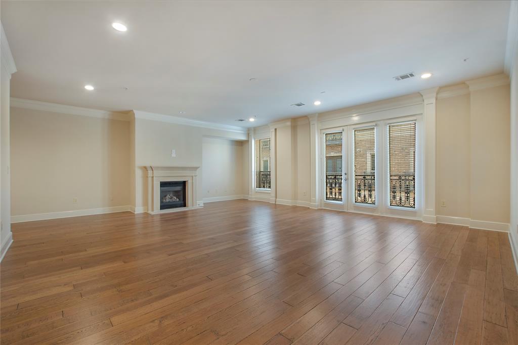 a view of an empty room with wooden floor fireplace and a window