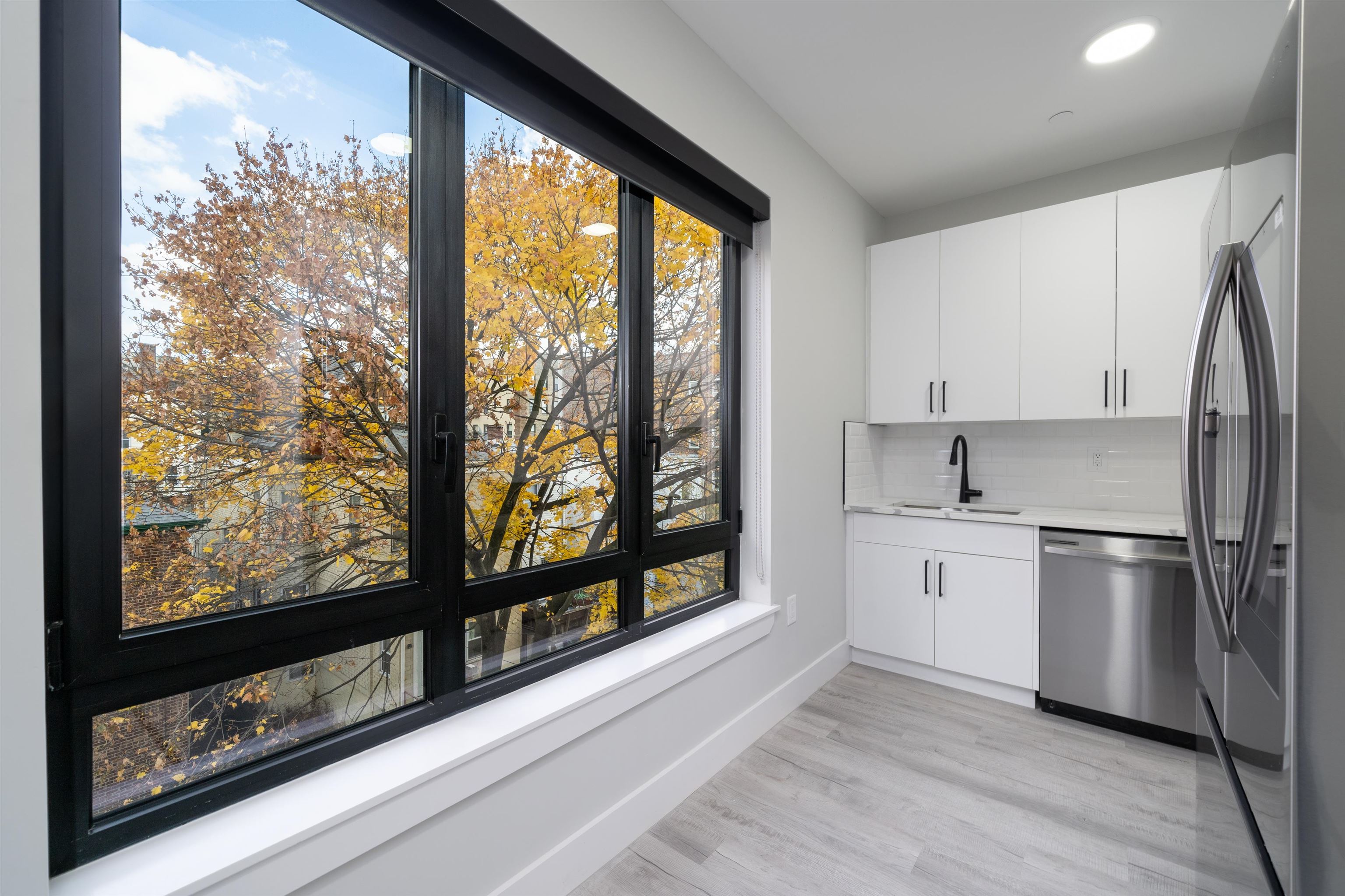 a kitchen with stainless steel appliances a sink cabinets and a large window