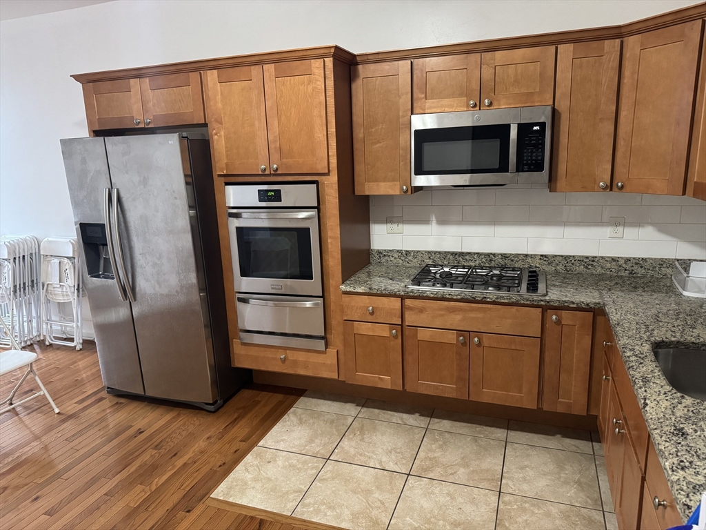 a kitchen with stainless steel appliances granite countertop a refrigerator and a stove top oven