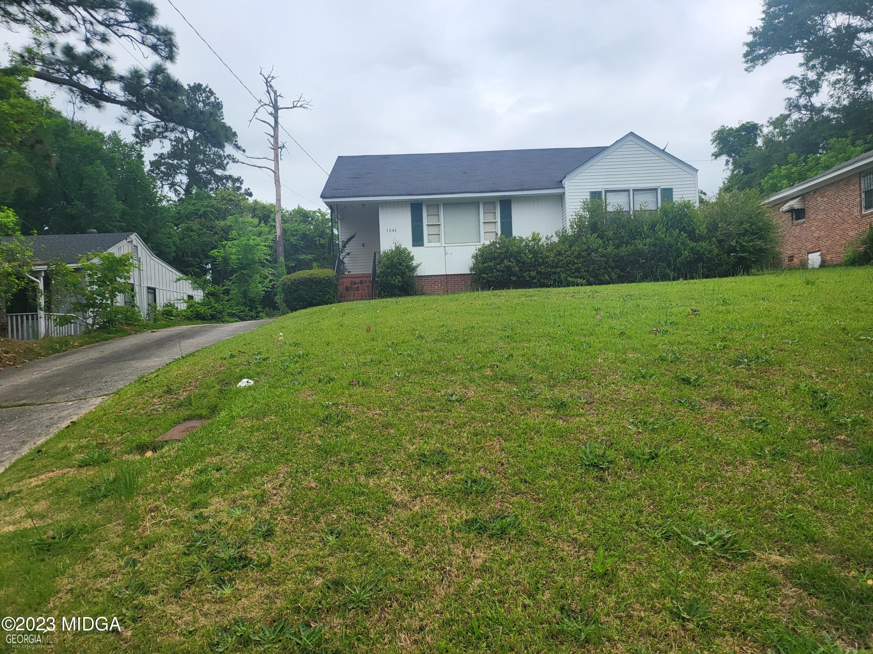 a view of a house next to a big yard and large trees