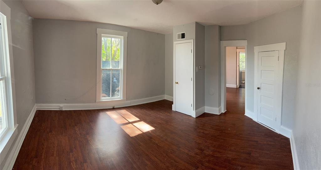 an empty room with wooden floor and windows