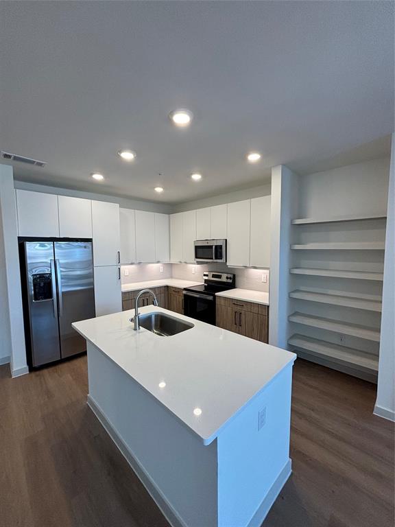 a kitchen with stainless steel appliances kitchen island sink refrigerator and cabinets