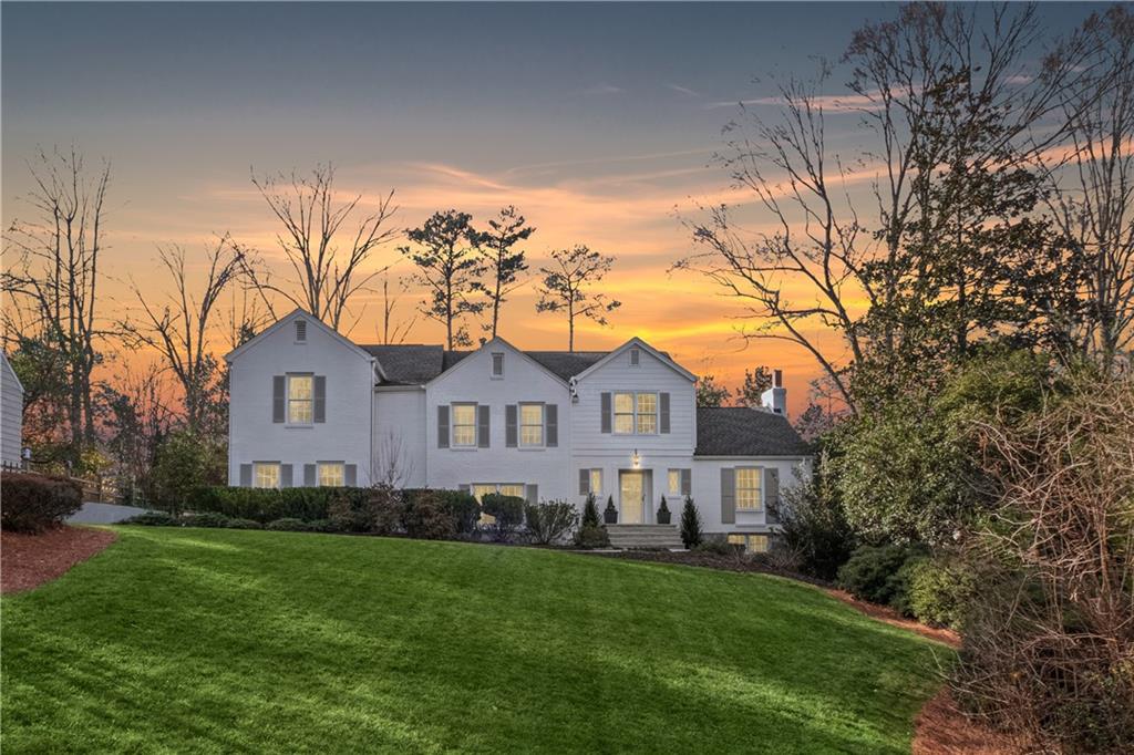 a front view of a house with a garden and trees