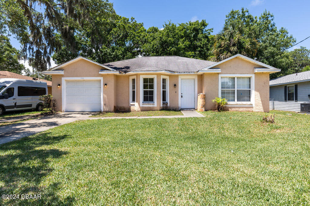 a front view of a house with a yard and trees