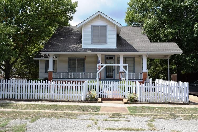 a view of a house with a small yard and wooden fence