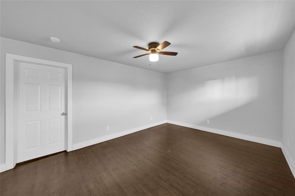 a view of an empty room with a ceiling fan and wooden floor