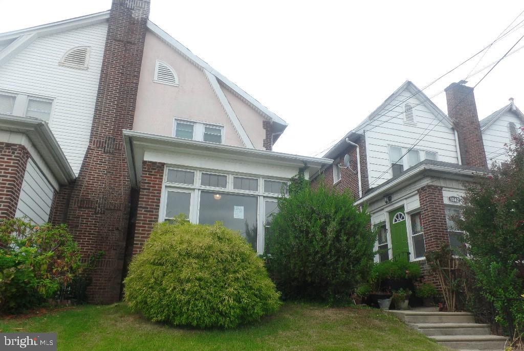 a view of a house with brick walls and a yard with plants