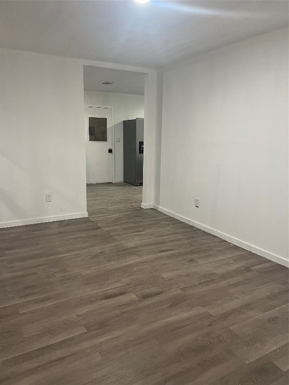 a view of an empty room with wooden floor and windows