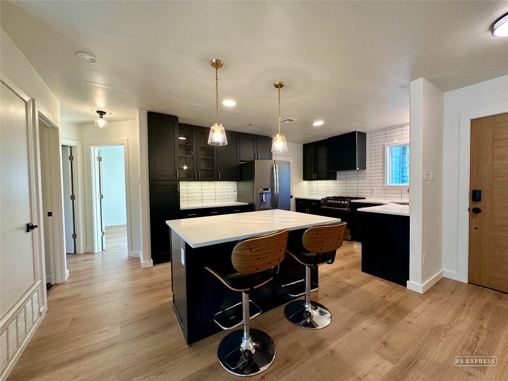 a kitchen with kitchen island stainless steel appliances a sink cabinets and wooden floor