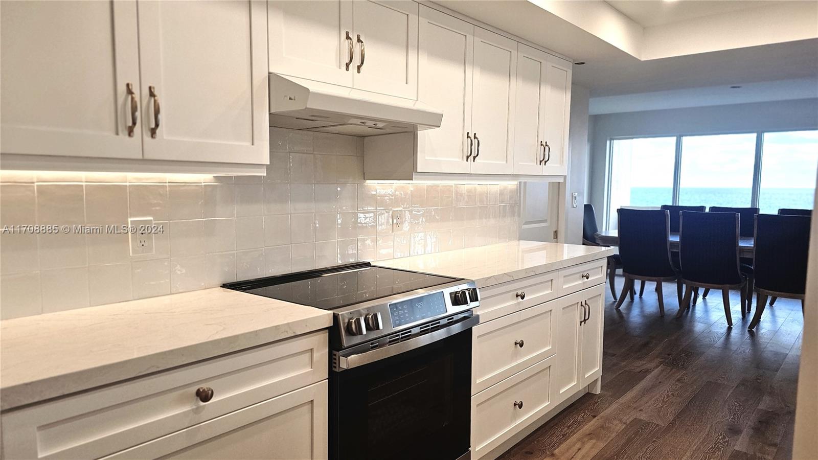 a kitchen with a stove and white cabinets with wooden floor