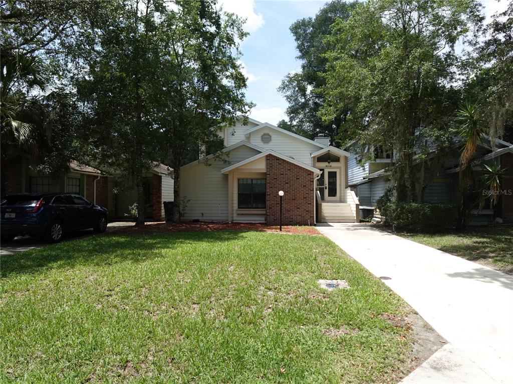 a front view of a house with a garden and trees