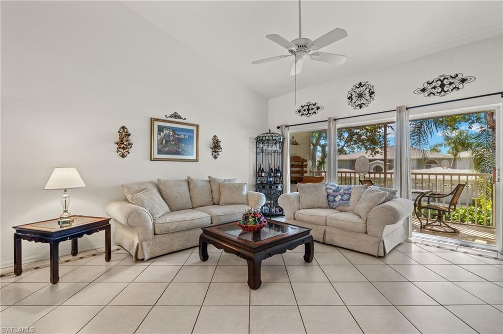 Living room with high vaulted ceiling, ceiling fan, and light tile patterned floors