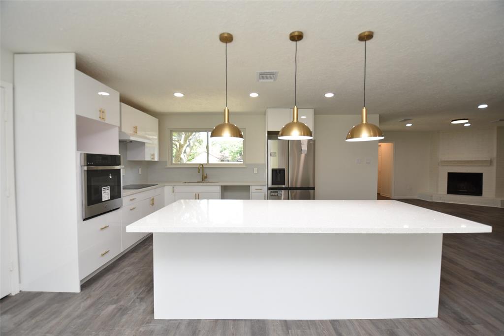 a room with kitchen island a sink wooden floor and a fireplace