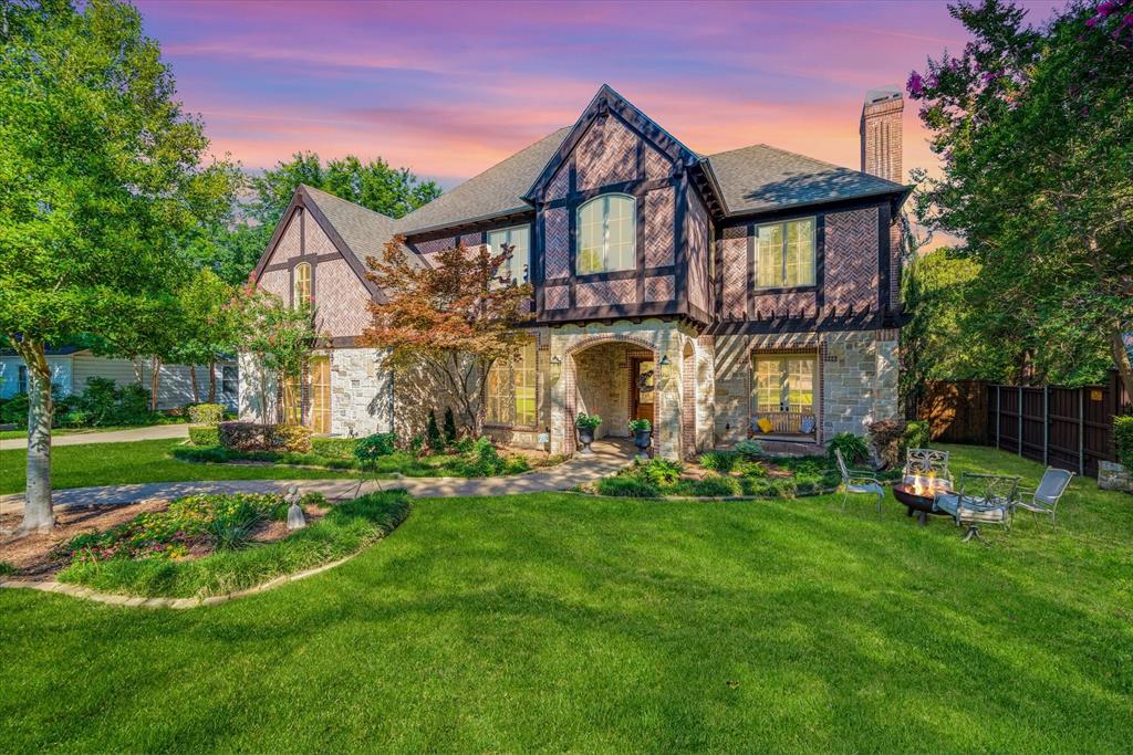 a view of a house with a big yard and potted plants and a large tree