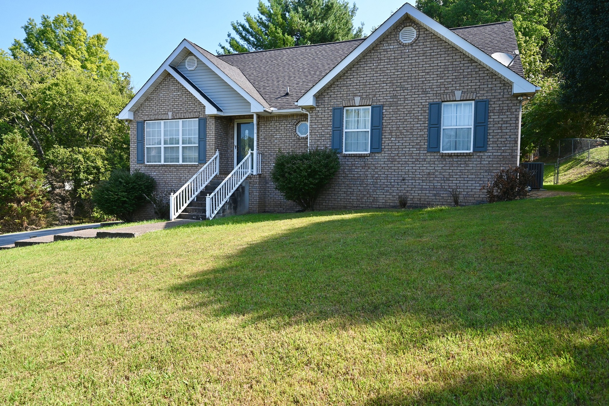 a view of a house next to big yard with large trees