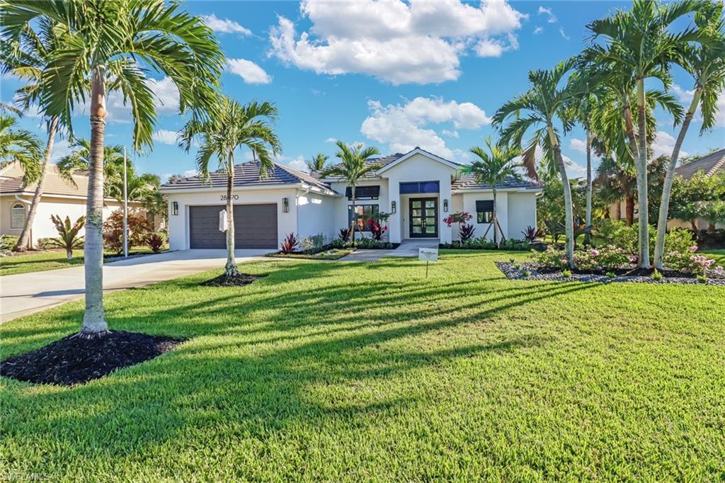 View of front of home featuring french doors, a garage, and a front lawn