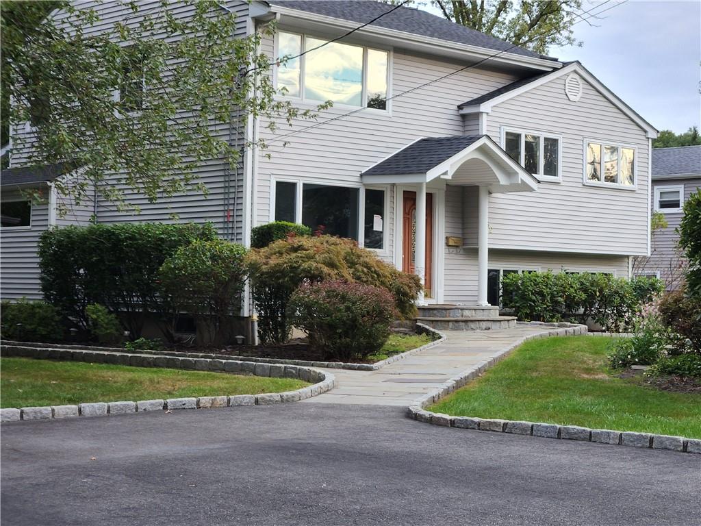 View of front of property featuring a front lawn and mature plantings.