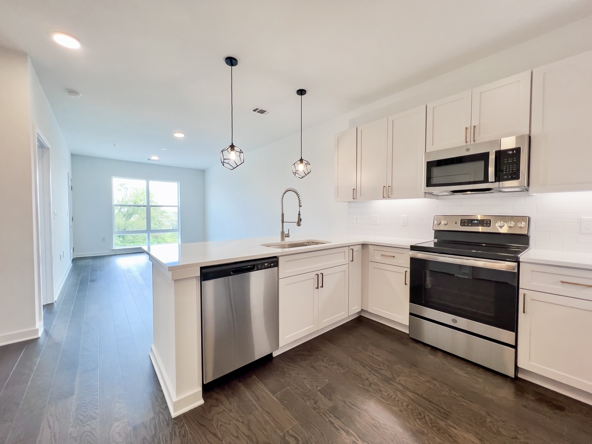 a kitchen with stainless steel appliances white cabinets a sink and wooden floor