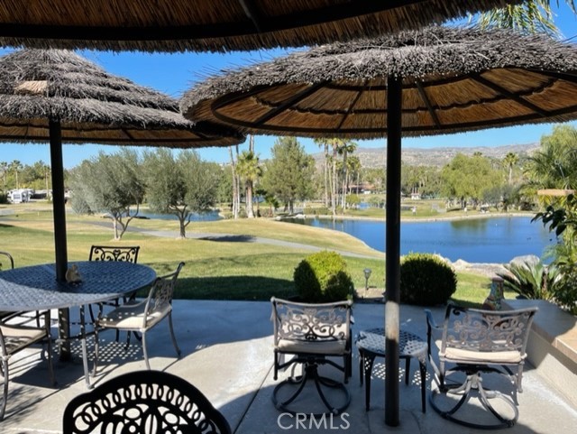 a view of a patio with table and chairs under an umbrella with a small yard