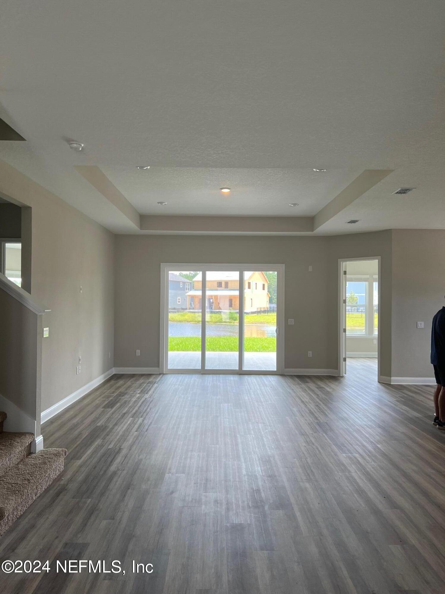 a view of an empty room with window and wooden floor