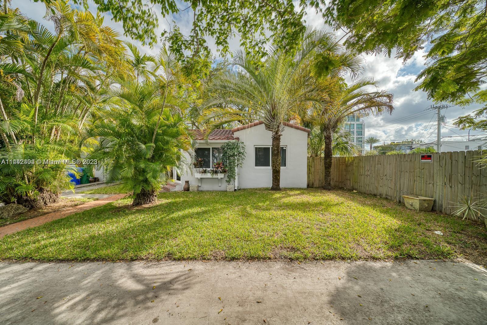 a view of a yard in front of a house with a large tree