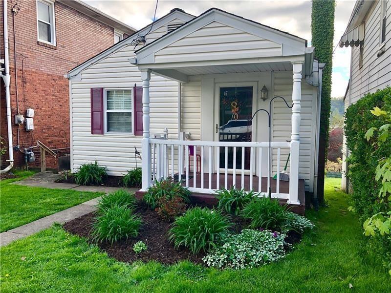 a view of a white house with a small yard and plants