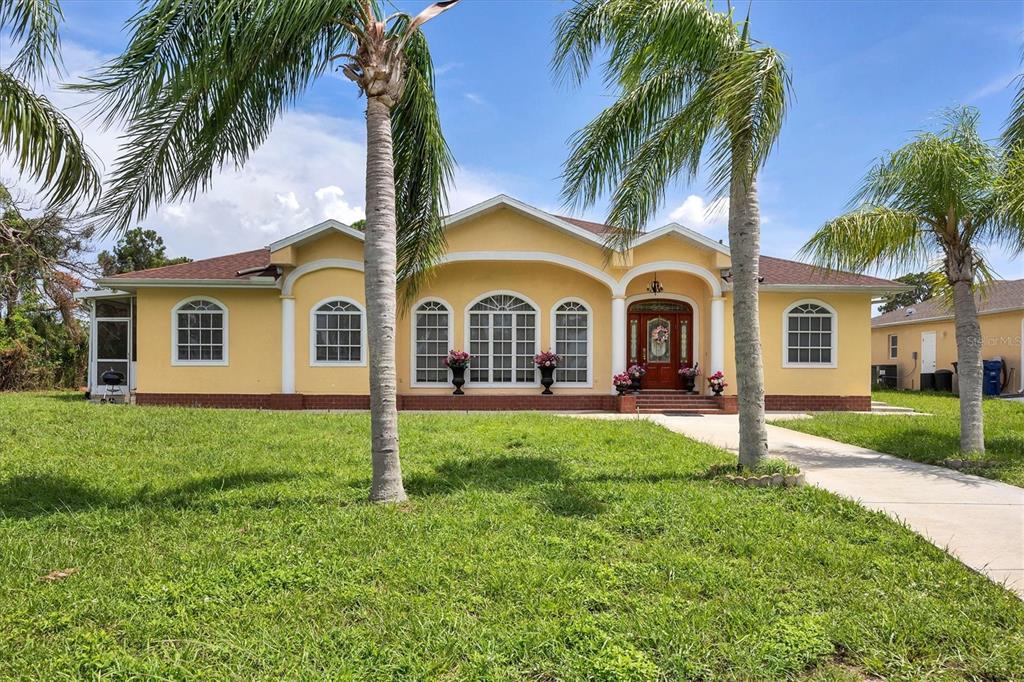 a view of a white house with a big yard and palm trees