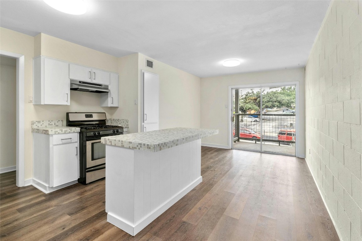 a kitchen with kitchen island granite countertop a stove and a wooden floors