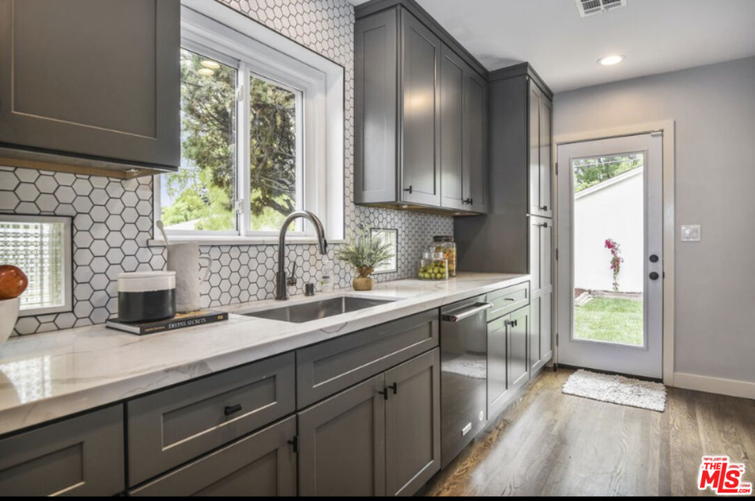 a kitchen with granite countertop a sink stainless steel appliances and cabinets