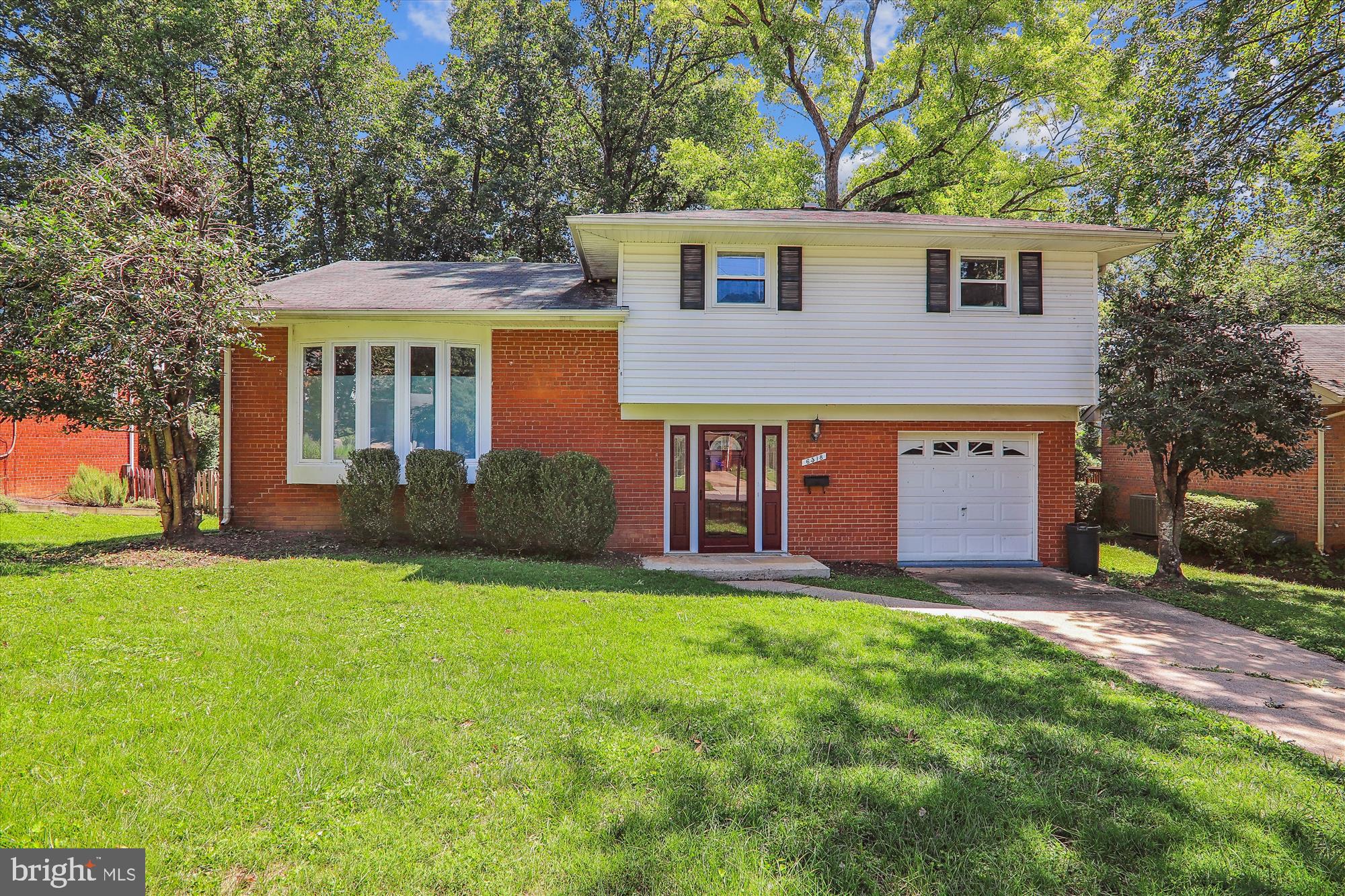 a front view of a house with a yard and trees