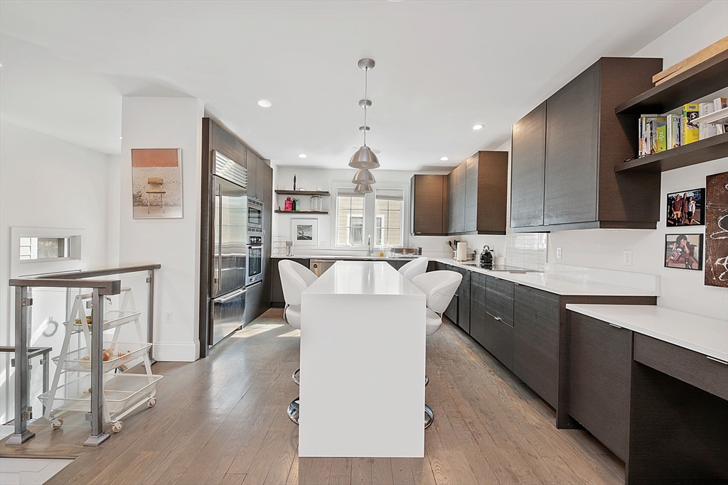 a large kitchen with stainless steel appliances kitchen island granite countertop a sink and a refrigerator