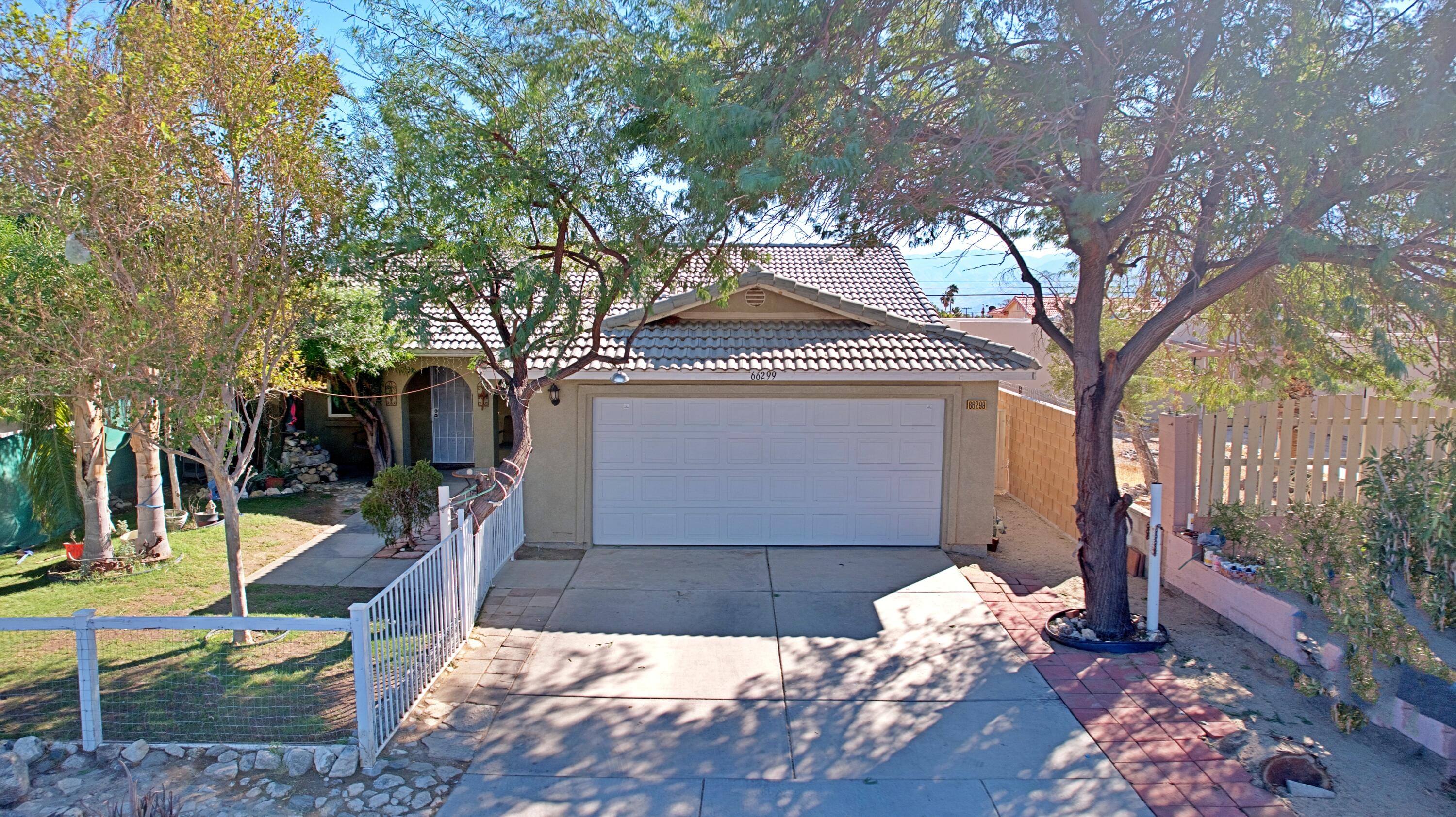 a view of a house with wooden fence and a tree