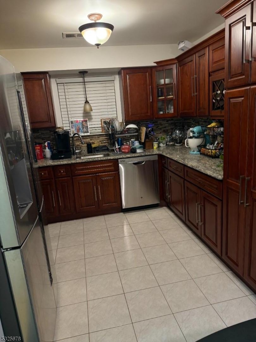 a kitchen with stainless steel appliances granite countertop wooden cabinets a stove top oven a sink and dishwasher