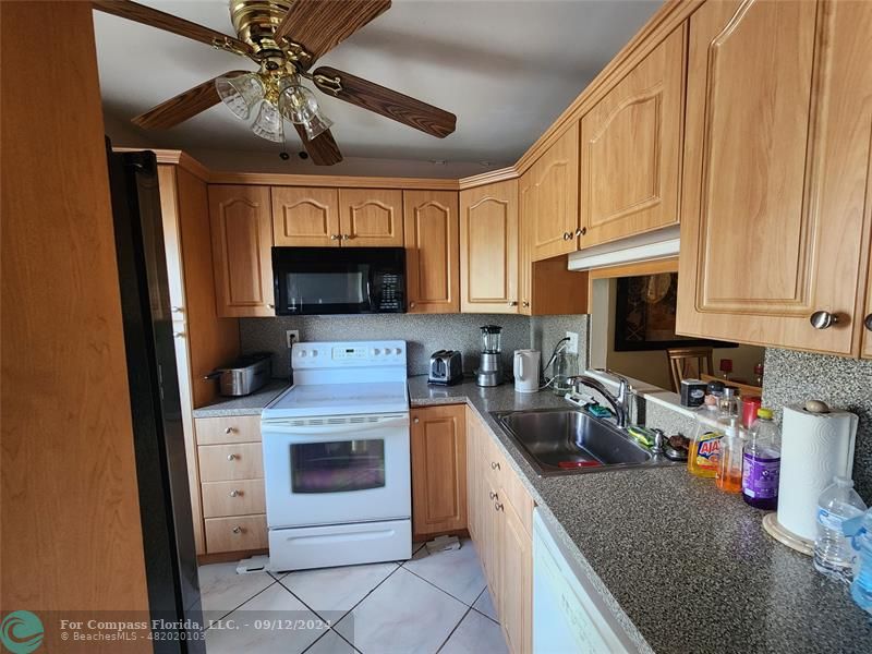 a kitchen with granite countertop a stove sink and cabinets