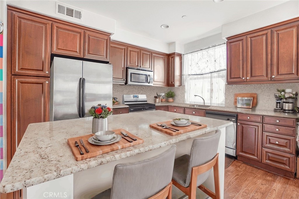 a kitchen with stainless steel appliances granite countertop a sink refrigerator and cabinets