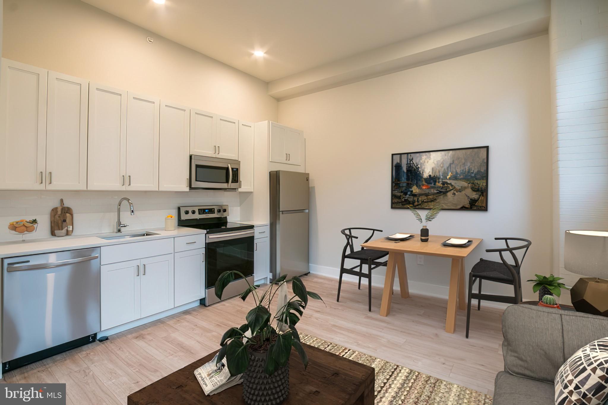 a living room with stainless steel appliances furniture a flat screen tv and kitchen view