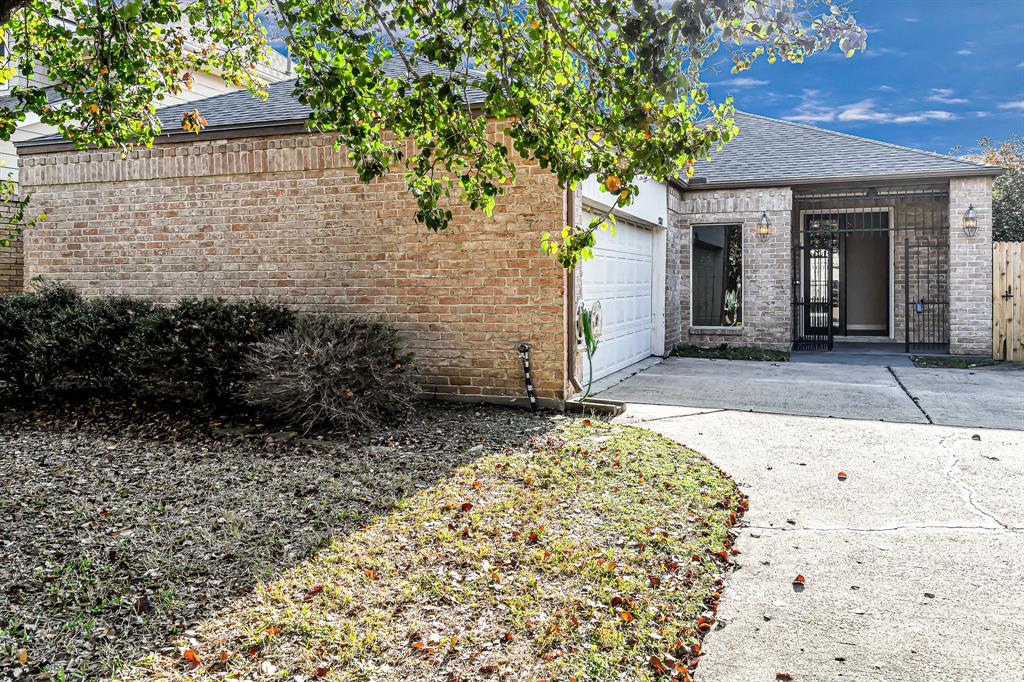 Welcome to our charming brick home with a two-car garage and a gated entryway. The front yard features mature trees and shrubs, providing a welcoming atmosphere.