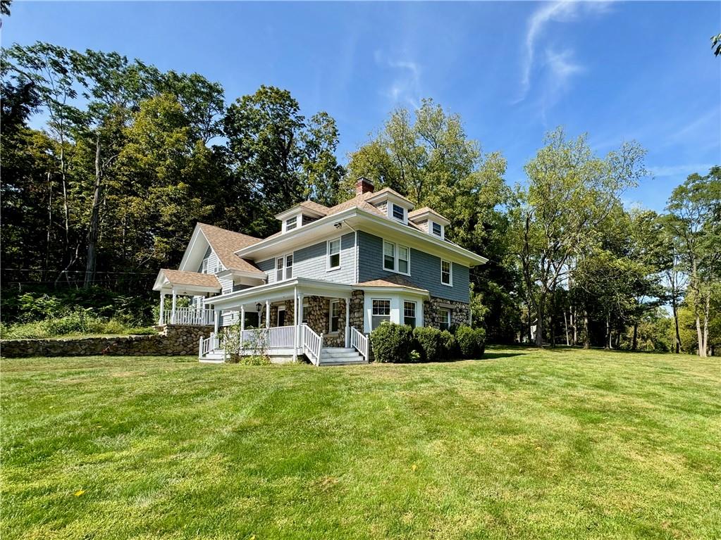 View of front wood & stone facade with covered porch overlooking front lawn