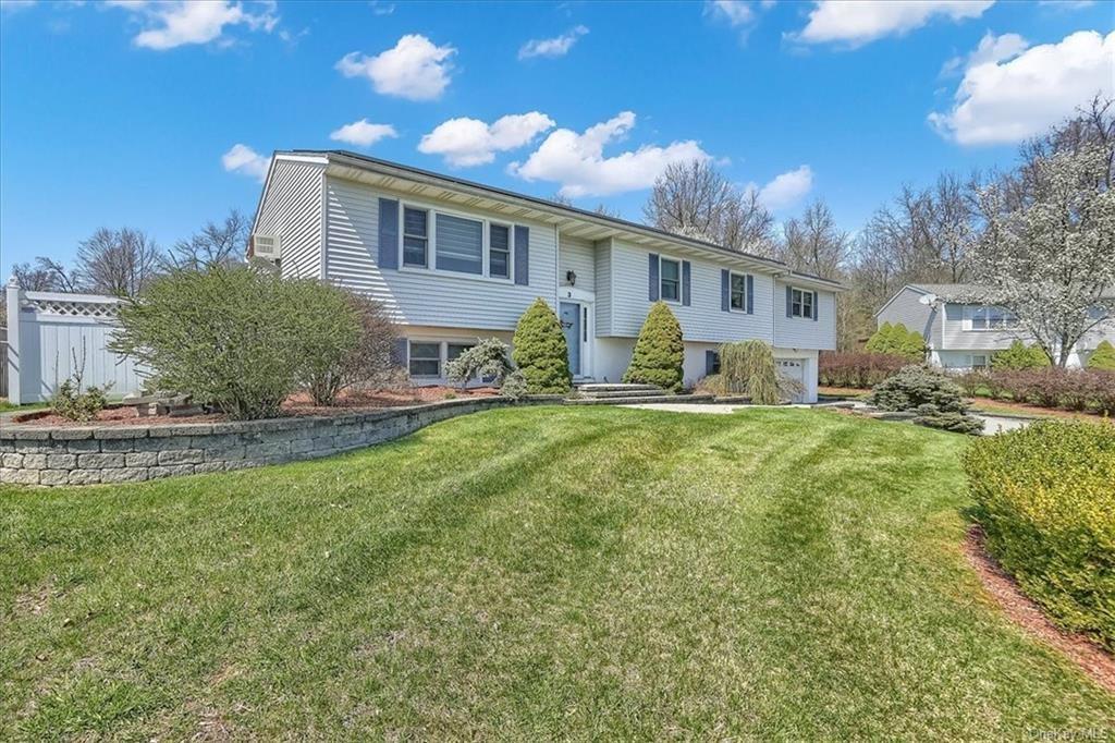 Bi-level home featuring a garage and a front lawn