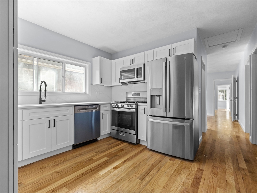 a kitchen with a refrigerator cabinets and wooden floor