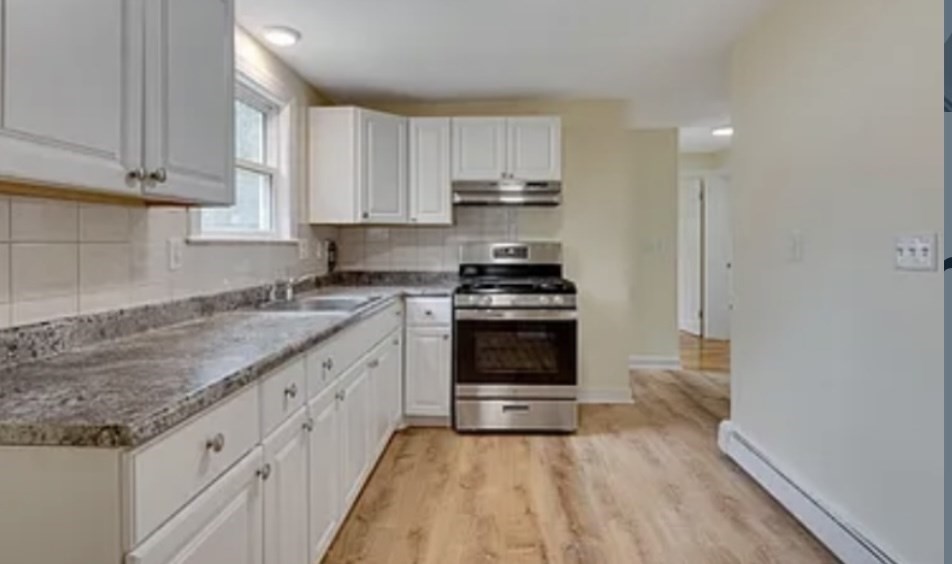 a kitchen with granite countertop a sink a stove and cabinets