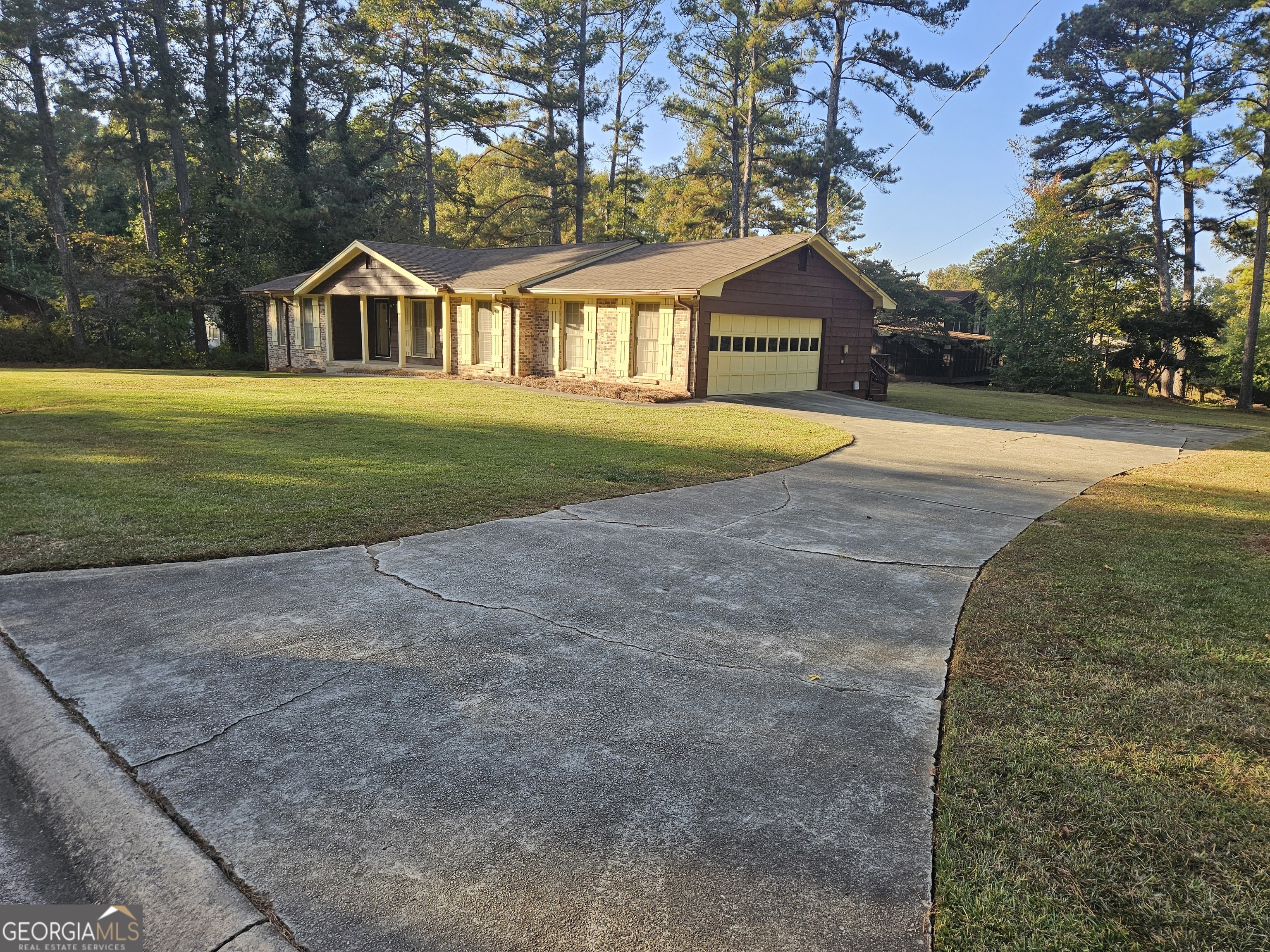 a view of house with a yard and large trees