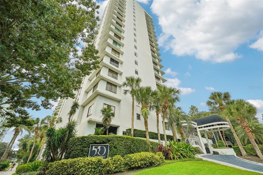 a front view of multi story residential apartment building with yard and parking space