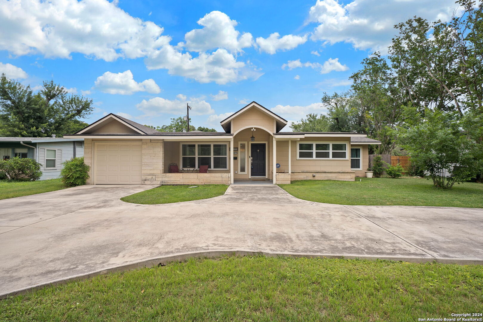 a view of house in front of a big yard with large trees