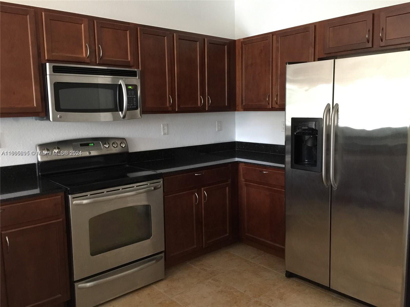 a kitchen with granite countertop wooden cabinets and stainless steel appliances